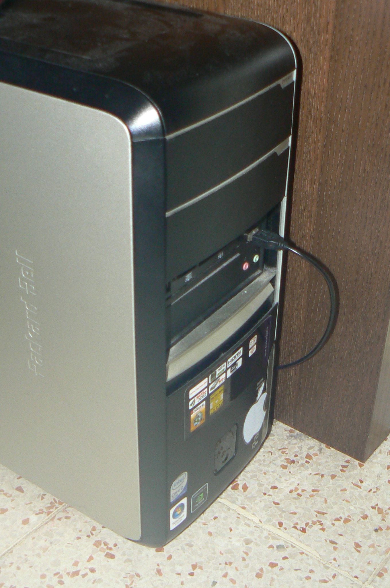 The front of the computer showing all the ports. The upper side is a bit dusty. There's an Apple sticker next to the power button.